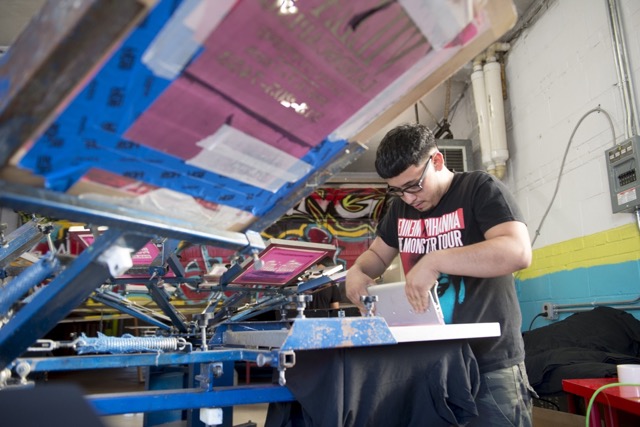 A member of Stitching Up Detroit inks a shirt at the screen printing facility at Grace in Action