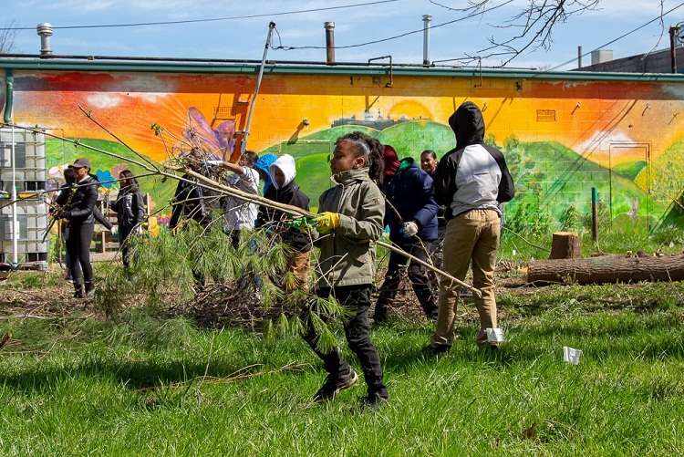 A youth gathers up loose wood during a Springboard to Excellence meetup.