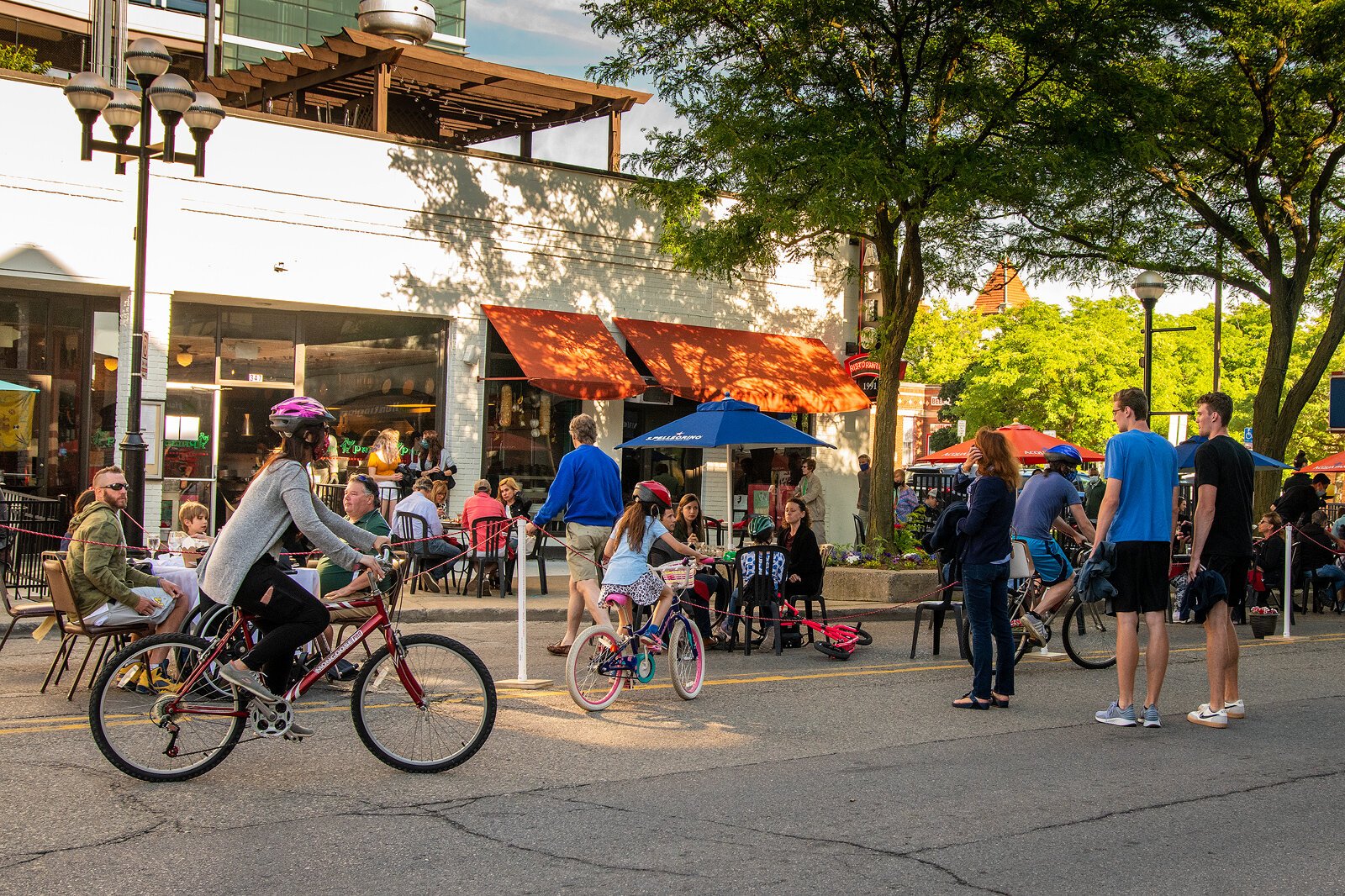 People walk and bike down Main Street in Ann Arbor.