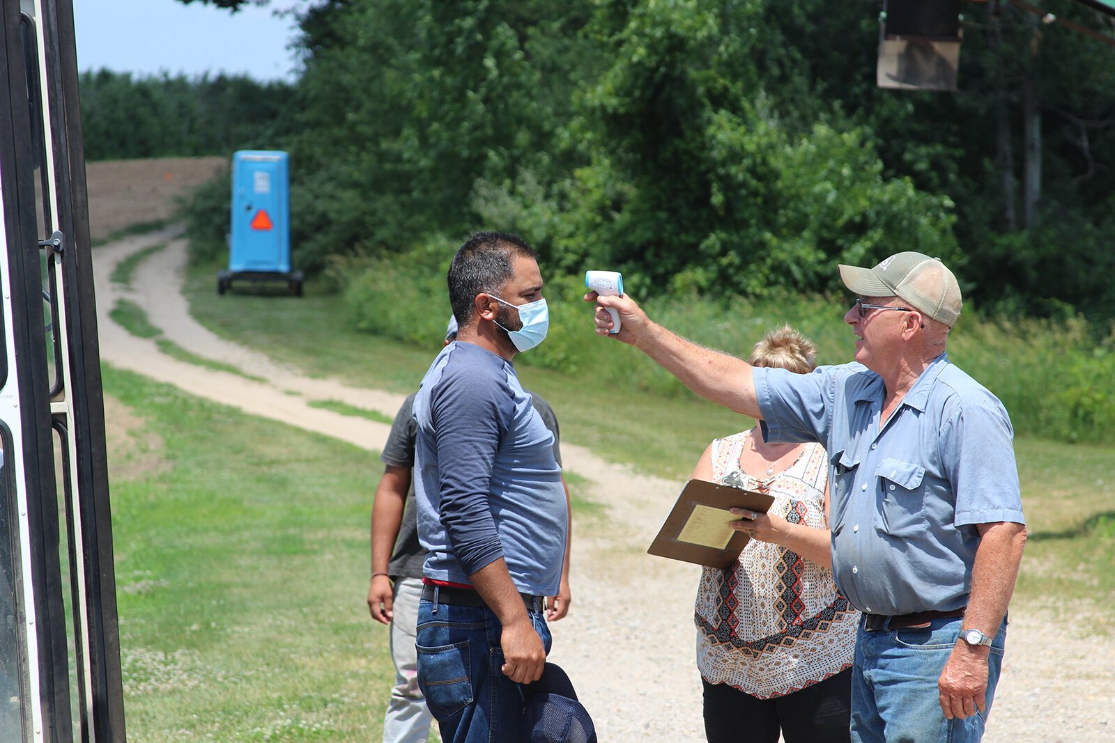 Belle Harvest farmer Tom Heffron checks a worker's temperature using a touchless thermometer.