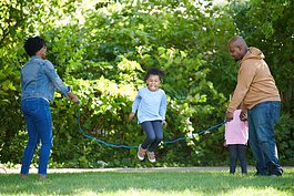 A family enjoys jump roping along the Lansing River Trail.