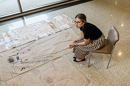 Dr. Sara Santarossa is the lead on a Henry Ford Health project that asked COVID long haulers to draw body maps representing their condition. She sits next to several of their works here.