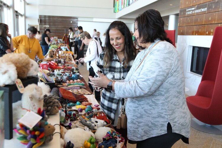 Karen Dowling and Denise Williams, of Muncie, Indiana, look at the handmade crafts on display at The Bridge vendor booth while attending the International Festival of Holland at the Holland Civic Center. (J.R. Valderas)