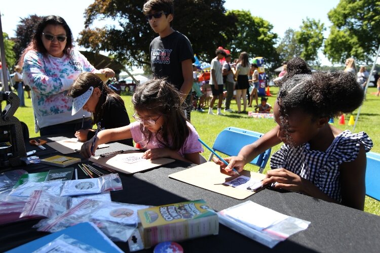 Visitors walk around the vendor booths and games in Kollen Park in Holland, Michigan while attending the I AM Academy's Juneteenth Freedom Festival, June 18, 2022.