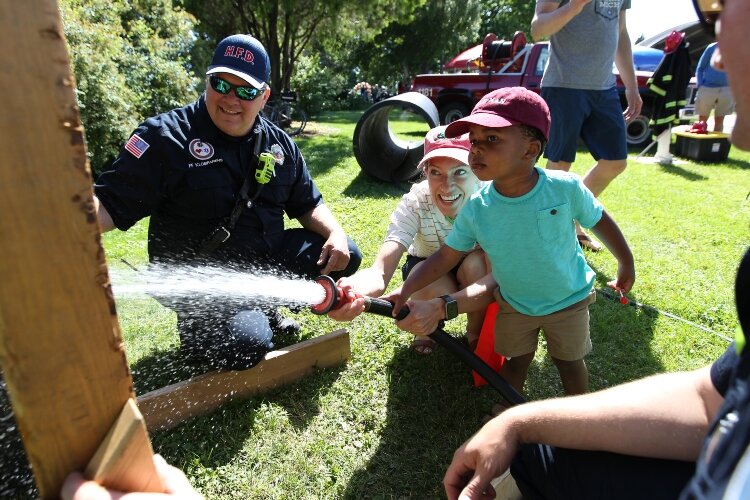 A youngster learns to extinguish a fire at the City of Holland's Fire Department booth while attending the I AM Academy's Juneteenth Freedom Festival in Kollen Park in Holland, Michigan, June 18, 2022.