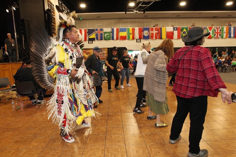 Gabriel Cleveland, of the Pokagon Band of Potawatomi from Dowagiac, leads visitors attending the International Festival of Holland in a circle while performing a round dance with them at the Holland Civic Center. (J.R. Valderas)