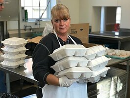Community Kitchen Assistant Rachel Nolan holds hot meals boxed and ready to go home with those who come to the soup kitchen daily.