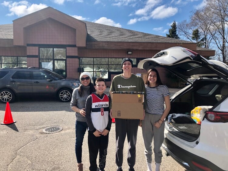 A family donates a box of food as part of the #StayHomeFightHunger challenge. 