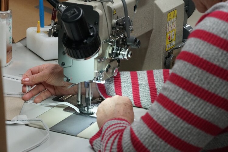 A Herman Miller employee sews a mask.