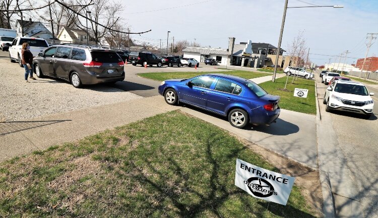 Customers of deBoer Bakkerij and Dutch Brothers Restaurant line up for weekly curbside service at the 16th Street location in Holland.