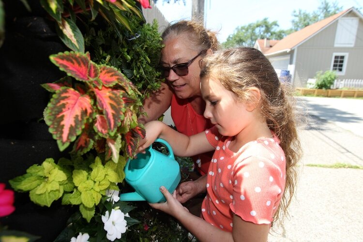 Bentley Weeks, 7, and Lori Appeldorn water the plants in the pockets of a Florafelt in the alley between 18th and 19th Streets along River and Central Avenues in Holland, Michigan, July 30, 2021.