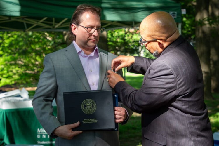 Michigan Department of Military and Veterans Affairs Director Brian Love awards Chris Petras with the Distinguished Service Medal on behalf of Gov. Gretchen Whitmer for Petras' work to honor WWI veterans who did not receive their Purple Hearts.
