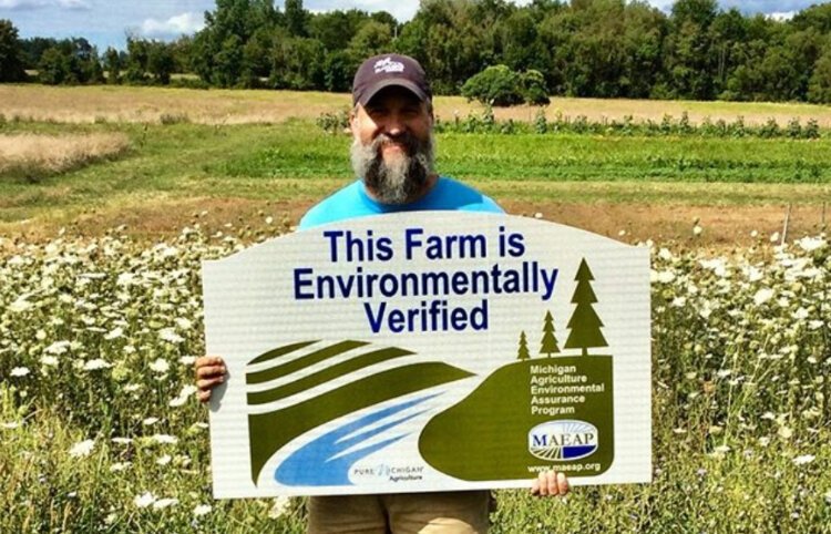 Greg Dunn's Blackbird Farm in Coopersville received MAEAP verification in 2020. Dunn shows off his new sign in one of their produce fields.