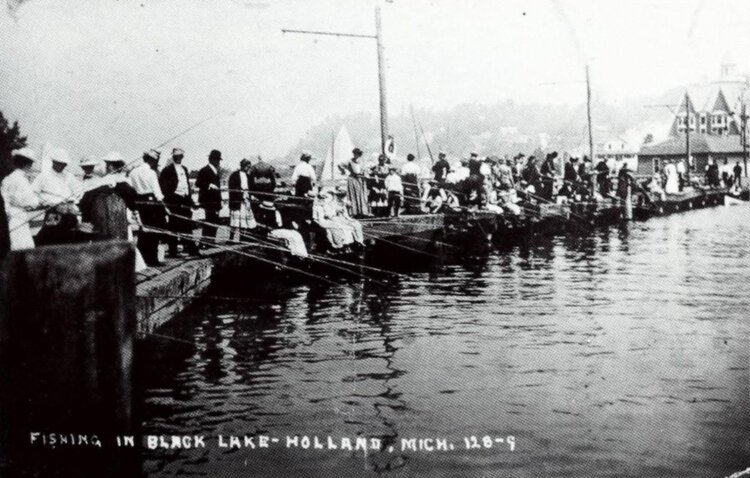 A vintage postcard shows dozens of people lining the shore of "Black Lake," what came to be known as Lake Macatawa, to fish.