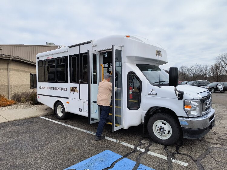 A passenger boards an Allegan County Transportation bus.