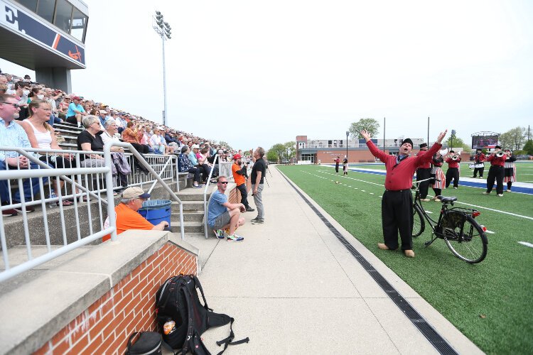 The conductor of Bicycle Showband Crescendo sings along with the 1,600+ in attendance at Hope College’s Ray and Sue Smith Stadium while the band performs Neil Diamond’s “Sweet Caroline” song during their debut performance at the Tulip Time Festival.