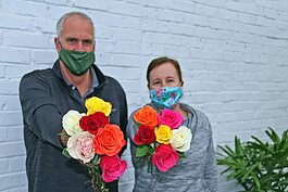 Dons Flowers and Gifts President Douglas J. Vos and office manager Katie DenHerder prepare to give away 3,500 roses to customers, so they can gift the flowers to friends and family in an effort to lift community spirits during the COVID-19 pandemic. 