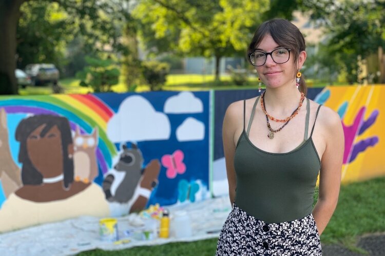 Eleanor Vega stands in front of the portion of the mural she painted titled "Unity.". 