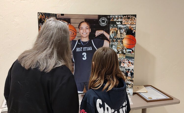 Two fans check out a photo display of Miss Basketball Michigan Gabby Reynolds before a Q&A session at Evergreen Commons.