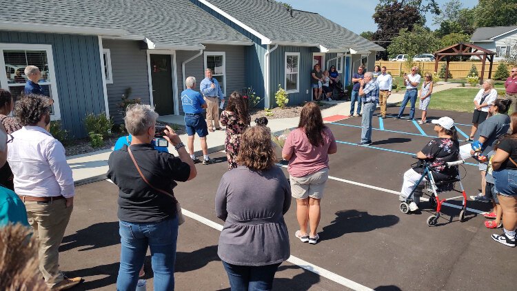 Supporters and future homeowners look on during the ribbon cutting ceremony for Lakeshore Habitat for Humanity's Haven Townhomes, which is specifically geared toward single adults with disabilities.