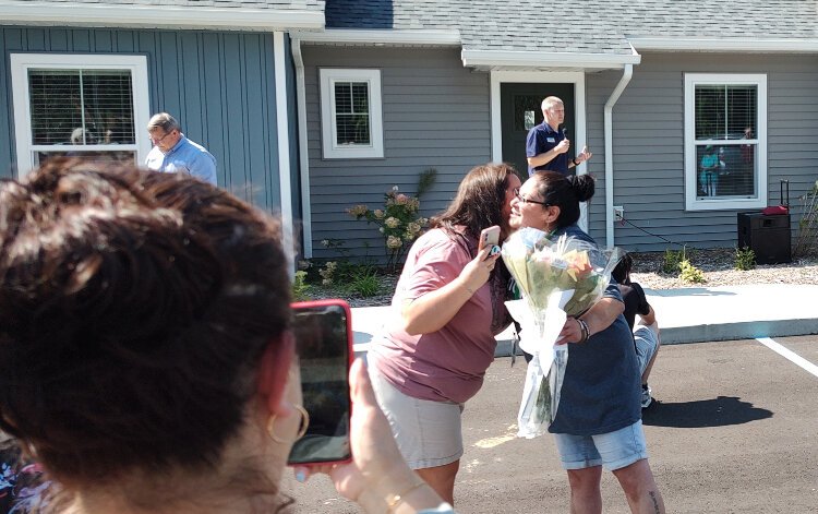 A future homeowner at Lakeshore Habitat's Haven Townhomes is hugged and given flowers during a ribbon cutting ceremony Wednesday afternoon, Aug. 16, 2023.