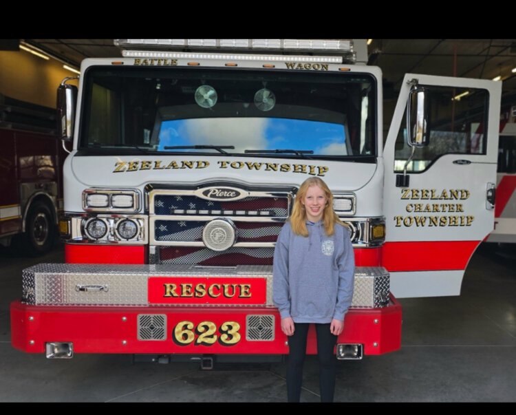 Eighth-grader Hayden Bruce poses with a fire truck after she used her bilingual education to help at a crash scene.