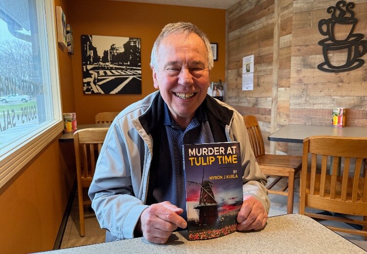 Holland author Myron Kukla with his novel, "Murder At Tulip Time."
