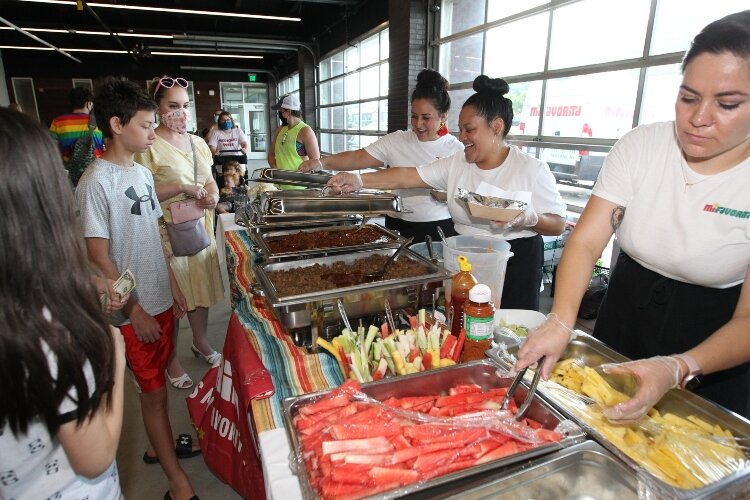 Dulce Martinez, Monica Bernabe and Jacqueline Navarrete, of Mi Favorita in Holland, Michigan, serve cups of fruit and tacos in the Festival Mercado section of the International Festival of Holland at the Holland Civic Center, August 21, 2021.