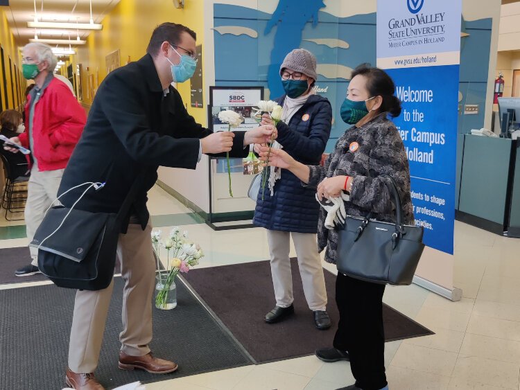 Mike Goorhouse, president/CEO of the Community Foundation of the Holland/Zeeland Area, offers flowers to members of the Asian community who were erroniously turned away from a vaccine clinic due to a computer error. 