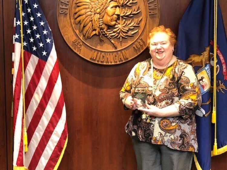 Ottawa County peer support specialist Kelly Chapman with the county customer service award she received for helping a client to vote for the first time.
