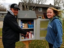 Jason Cottrell and his daughter, Gracie Jo, 11, pose in front of the little free pantry their family created in front of their home, 1237 Marlene St. Holland.