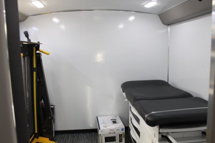 The mobile unit contains two exam rooms, a lab with a medical refrigerator, a waiting area, and a restroom.