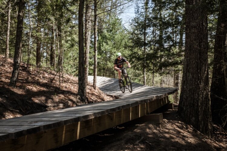 Mark Stoll rides over a Mosquito Creek Trails bridge built to protect a bank from erosion. The bridge was built entirely by volunteers who hauled all the materials through the woods by hand. 