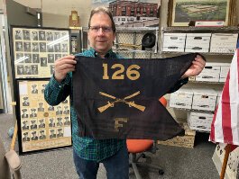 Dr. Chris Petras holds up the flag of the 126th Infantry/Regiment, WWI.