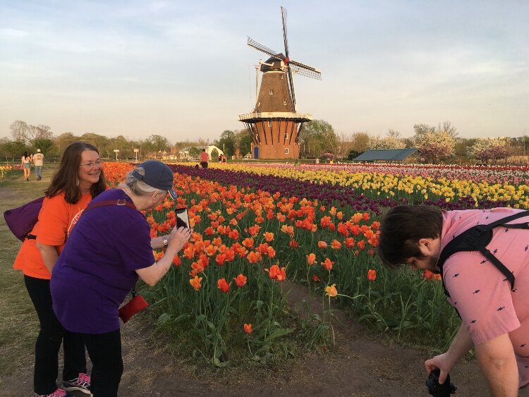 Heidi Quellet, a photographer of “Art and Praise,” left, assists a  participant of the Tulip Time Festival’s Photo Walk workshop   while showing photographers how to document DeZwaan Windmill with the tulips at Windmill Island Gardens, May 12.