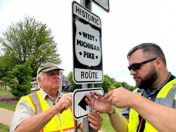 Local historian Blaine Knoll (left) and Ottawa County Land Use Specialist Andrew Roszkowski install a new West Michigan Pike sign in Holland earlier this month. [Rich C. Lakeberg/Ottawa County]