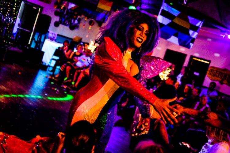 Drag Queen La Reine Divine accepts tips from the audience during their performance during the White Party and Pride Ball.