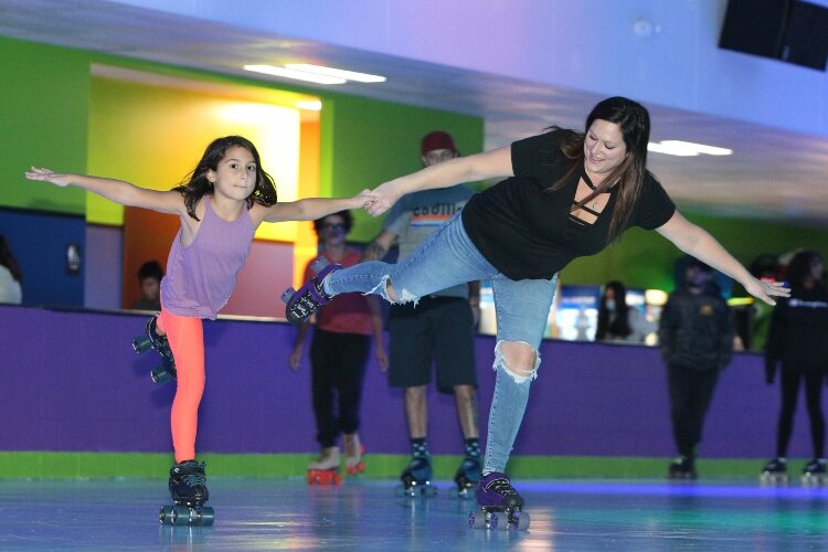 Jamie Guilmett, of Holland, and her daughter Jayla, 8, glide together on one foot while roller skating at RollXscape Skating Center’s grand opening in Holland Township, Nov. 4.