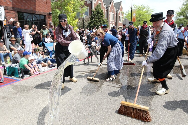 Holland Mayor Nathan Bocks, right, and residents scrub 8th Street in downtown Holland before the Tulip Time Festival’s Volksparade on May 14. 