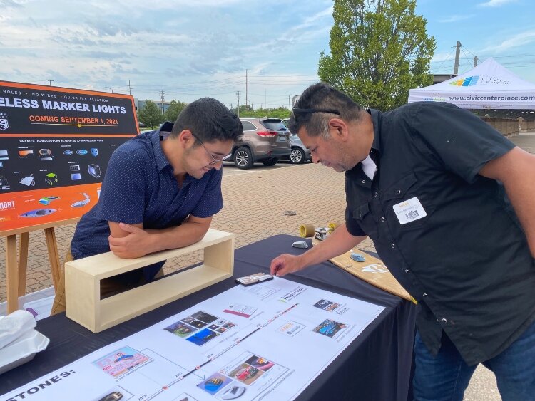 Entrepreneurs Luciano Hernandez V and his dad, Luciano Hernandez IV, show off their product at the Surge Celebration. 