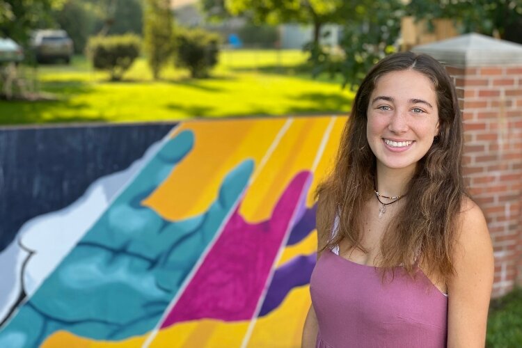 Tori Airo stands in front of the mural she created titled "Alive In Nature.” 