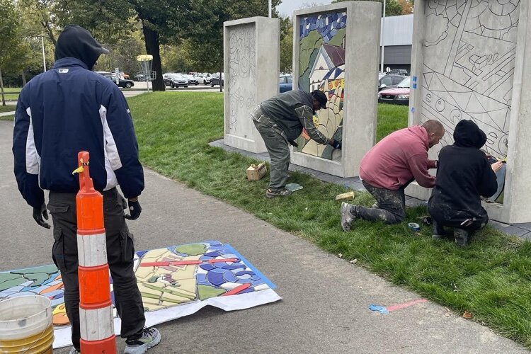 Muralist Hubert Massey works on the center of the triptych at Lawrence Tech, while his assistants work on the right.