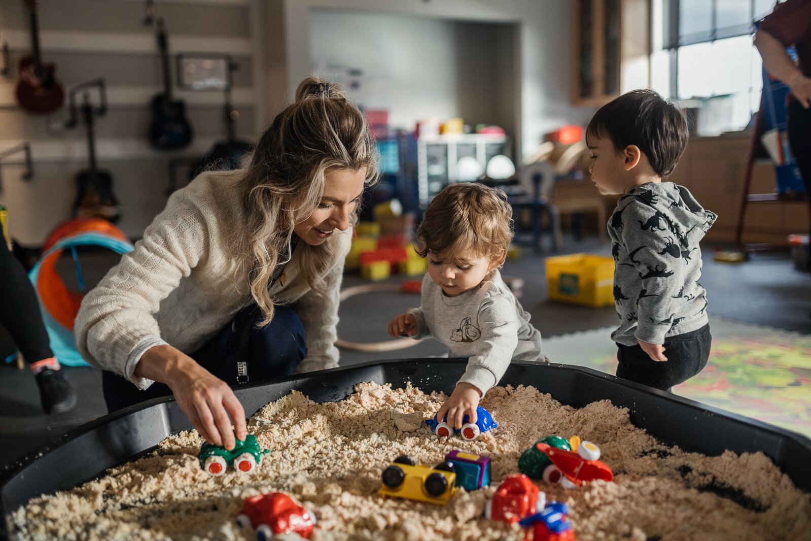 Katie Geekie, early childhood development coordinator at the Chaldean Community Foundation, plays in the sandbox there with James and Levi.