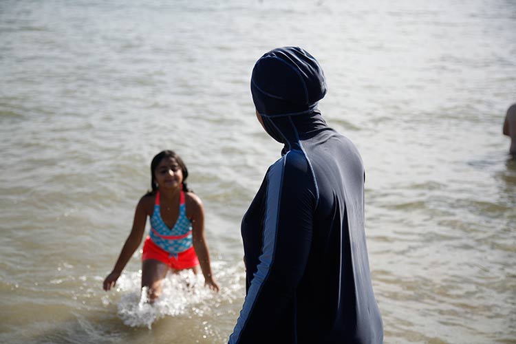 E.H. taking her daughter for a swim at Cass Lake. Photo by Imad Hassan.