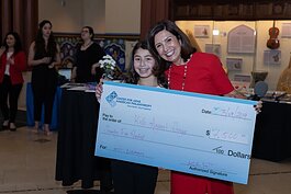 Rasha Demashkieh presents a check to the winner of the 100 Arab American Women Who Care event in 2019.