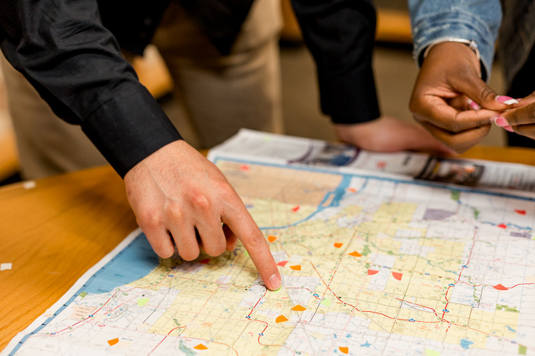 Momar Almadani and Yarnise Hines adding stickers to a map of Metro Detroit, indicating areas they have impacted through their studies.