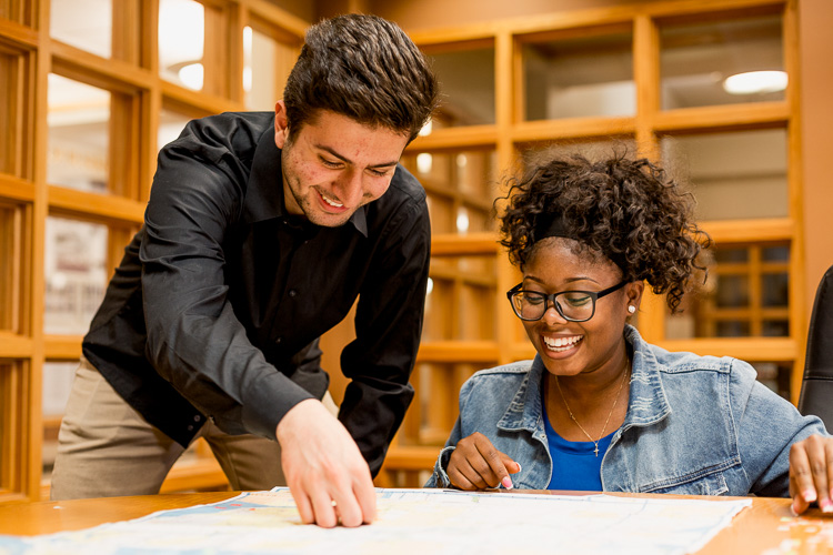 Momar Almadani and Yarnise Hines adding stickers to a map of Metro Detroit, indicating areas they have impacted through their studies.