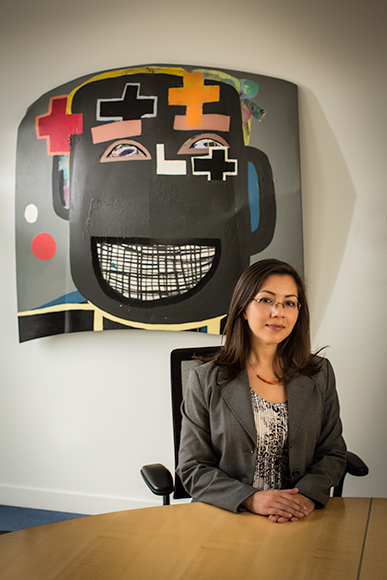 Leila Matta, Art Programs Manager, sits in an executive conference room at the Mercedes-Benz Financial Services headquarters. In the background is a painting from Tyree Guyton’s Heidelberg Project which is part of the company’s permanent art collecti