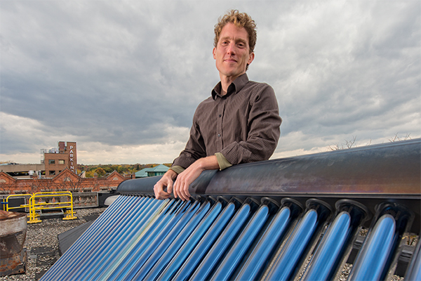 Jacob Corvidae with a solar water heater on the roof of the Washtenaw County Administration Building