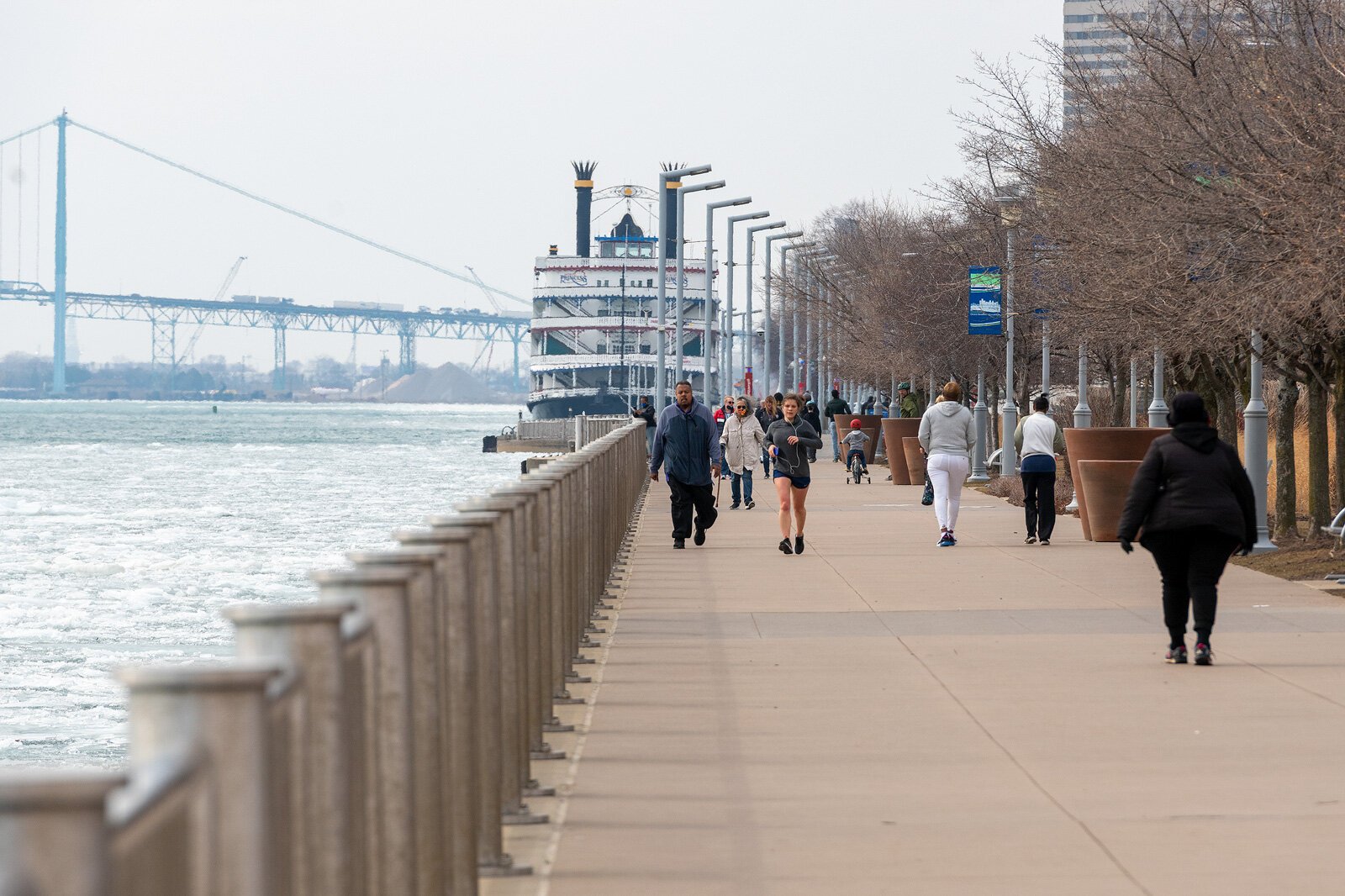 People walk and run on the Detroit Riverwalk.